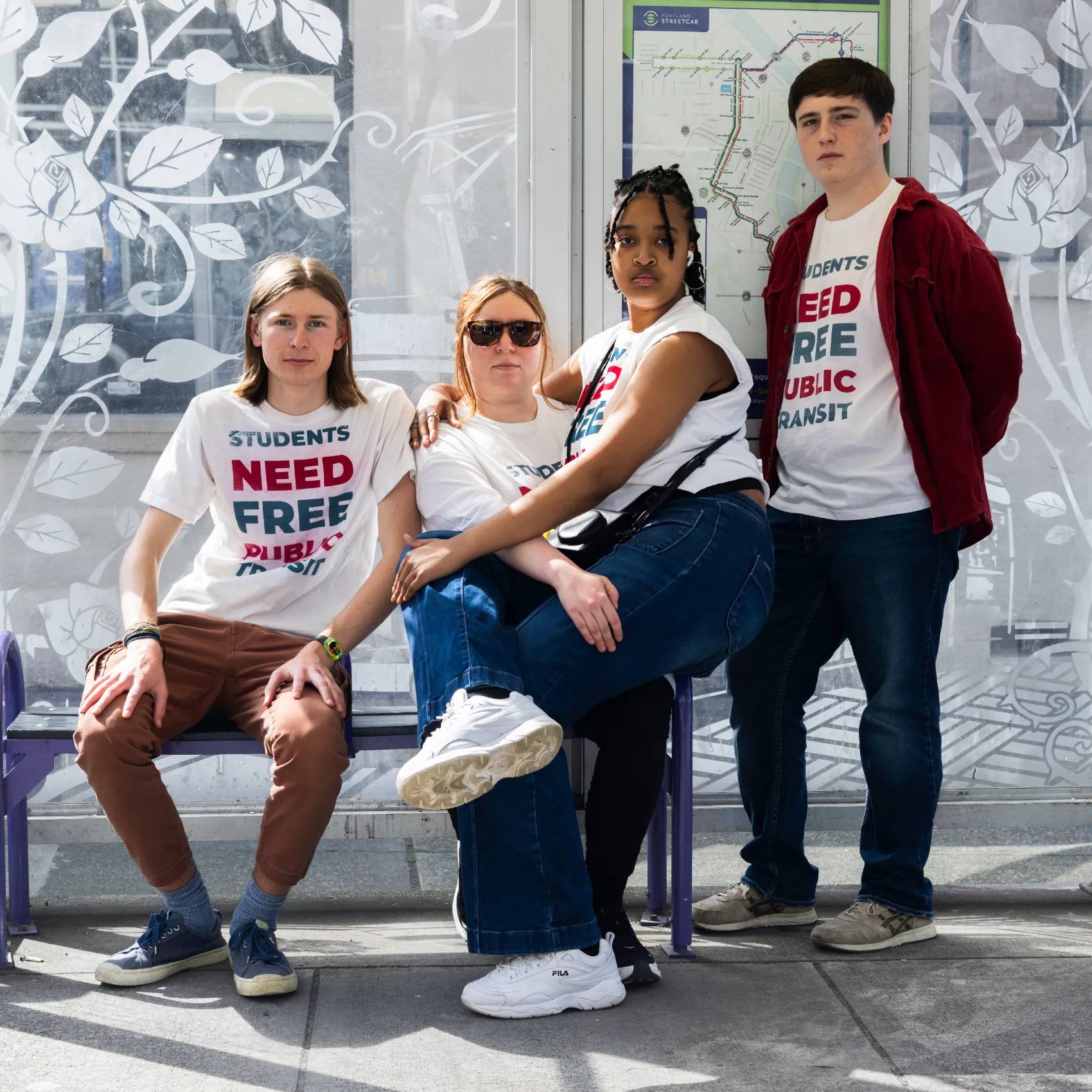 Students wering matching t-shirts sit on bus bench